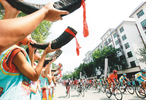 10月20日,车手骑行经过保亭县城,当地用极具民族特色的方式欢迎各国选手。 本报记者 宋国强 摄